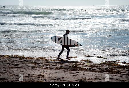 Pembrokeshire, pays de Galles. Plage de West Dale. Surfeur sur le point d'aller dans la mer. Banque D'Images