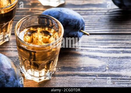 Slivovica - brandy de prune ou vodka de prune, liqueur dure, boisson forte dans des verres sur une table en bois ancienne, prunes fraîches, espace de copie Banque D'Images