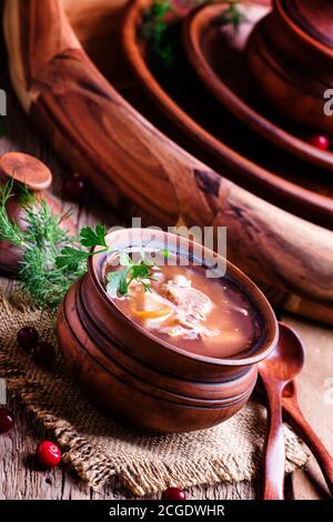 Soupe russe traditionnelle de choucroute, viande et pommes de terre dans un pot d'argile, fond de bois vintage, style rustique, concentration sélective Banque D'Images