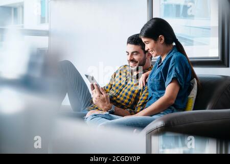 Couple heureux de rire tout en regardant la vidéo sur tablette Banque D'Images