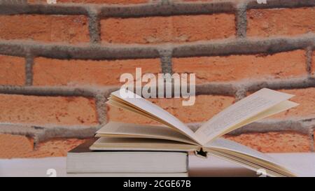 Pile de livres d'étude, avec livre ouvert sur fond blanc et mur de briques, zoom, photo conceptuelle Banque D'Images