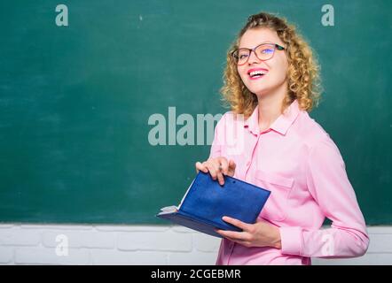 Professeur meilleur ami des apprenants. Femme enseignante devant le tableau de surveillance. Passionné par la connaissance. Pédalo tenir le livre et expliquer l'information. Concept d'éducation. Le professeur explique le sujet dur. Banque D'Images