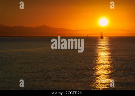 Bateau de pêche au coucher du soleil dans le détroit de Georgia. Un bateau à poissons revenant du détroit de Georgia et de la mer Salish au coucher du soleil. L'île de Vancouver en arrière-plan. Banque D'Images