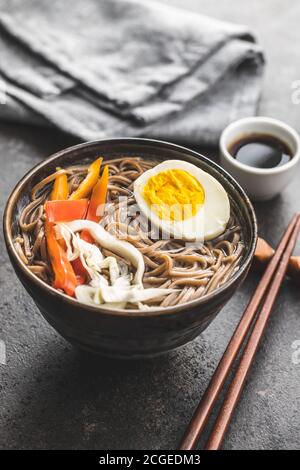 Soupe asiatique de nouilles avec nouilles soba, légumes et œufs dans un bol. Banque D'Images