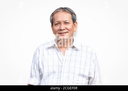 Portrait d'un homme asiatique senior souriant debout devant un arrière-plan blanc avec confiance en soi. Gros plan sur le visage de l'ancien sourire avec des cheveux gris. Banque D'Images