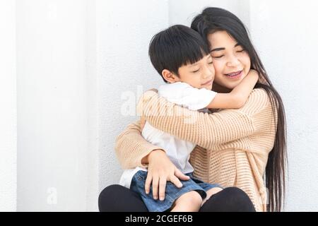 Portrait belle mère et enfant heureux embrassé. La mère et l'enfant de la famille asiatique s'embrasent et ferment les yeux, mignons et chauds. Banque D'Images
