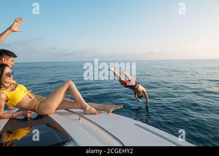 Groupe d'amis voyageant sur un yacht moderne à mer ouverte, et bénéficiant d'une belle journée d'été. Congé, vacances, été, concept. Banque D'Images