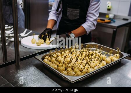 Un cuisinier en gants noirs prépare des boulettes de fromage. Concept de restaurant. Banque D'Images