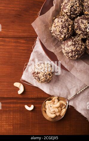 Boules de cacao, gâteaux de truffes au chocolat à bord sur fond de bois noix de cajou saupoudrées Banque D'Images