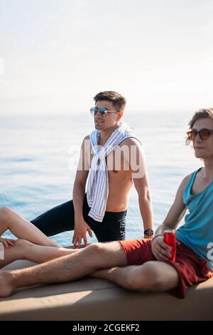 Deux heureux amis mâles caucasiens voyageant sur un yacht à la mer ouverte . Vacances, tourisme, vacances, concept. Banque D'Images