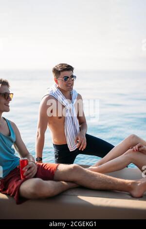 Deux heureux amis mâles caucasiens voyageant sur un yacht à la mer ouverte . Vacances, tourisme, vacances, concept. Banque D'Images