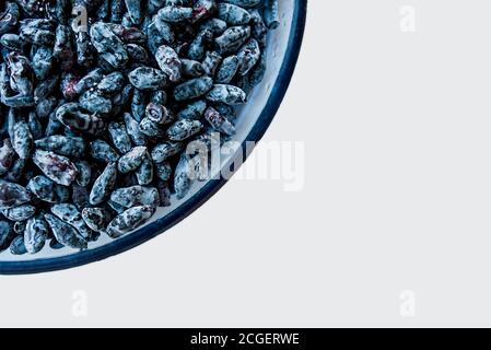 lot de la même mûre juteuse bleu baies de chèvrefeuille dans des gouttes d'eau dans une plaque de verre bleu sur une table blanche, vue de dessus. Fond Berry ou fond d'écran Banque D'Images