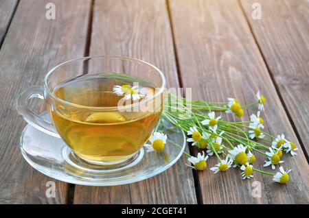 Thé chaud à la camomille fraîchement préparé dans une tasse de verre sur une table en bois. Concept de thé sain. Banque D'Images