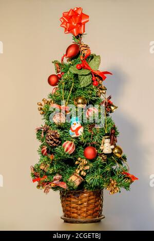 Arbre de Noël vert décoré avec des figures typiques de la date, avec des boules rouges, avec des mini-cadeaux, et un noeud rouge au sommet de l'arbre Banque D'Images