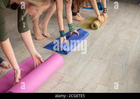 Yoga les élèves féminins avant ou après la pratique du yoga, se préparant à l'exercice, à dérouler ou à rouler un tapis de yoga coloré Banque D'Images