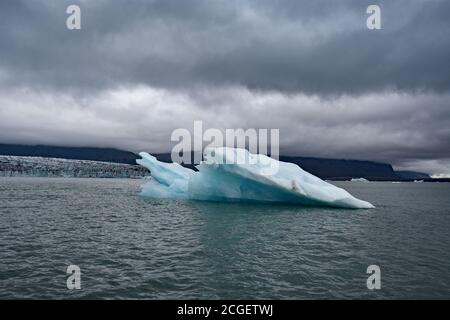 Un grand iceberg bleu flotte seul devant Breiðamerkurjökull dans la lagune du glacier de Jokulsarlon, dans le sud de l'Islande. Banque D'Images