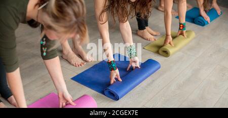 Les mains des femmes déroulent le tapis de yoga avant l'exercice. Concept de mode de vie sain, vue d'en haut. Banque D'Images