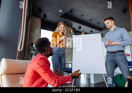 Jeune entraîneur d'affaires, homme et femme, employé de bureau préparant la présentation debout ensemble devant un tableau de conférence avec un graphique sur elle Banque D'Images