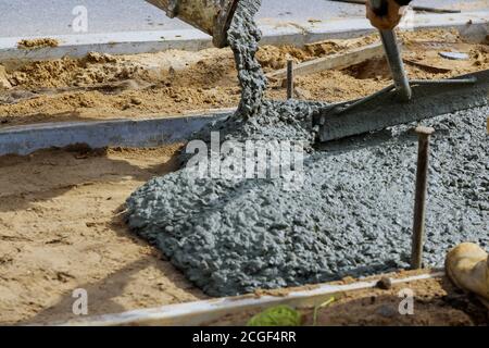 Mélangeur en béton pour les travailleurs avec ciment versant sur le trottoir résidentiel Banque D'Images