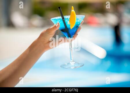 Femme dans la piscine s'étirant la main avec une boisson. L'accent est mis sur le verre à cocktail avec margarita de fraise. Repas et boissons en vacances Banque D'Images