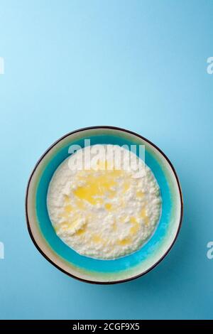 Portion chaude de porridge de riz dans un bol sur fond bleu Banque D'Images