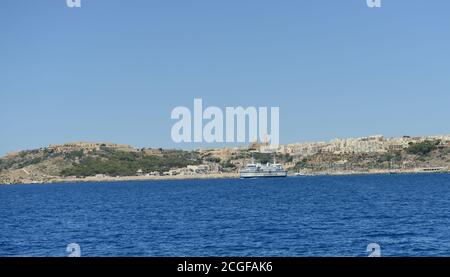 Vue sur le port de plaisance et l'église de la Madonna de Lourdes à Triq Lourdes, Għajnsielem, Malte. Banque D'Images