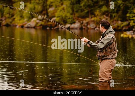 Pêcheur utilisant la pêche à la mouche dans la rivière de montagne Banque D'Images