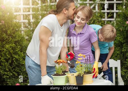 Parents aimant avec fils plantant des fleurs dans des pots dans la ferme de plantation . Garçon aide les parents. Horticulture. Fleurs. Plantation de fleurs. Outils de jardinage Banque D'Images