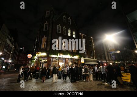 Jeunes à l'extérieur du pub Blue Posts à Berwick Street, Soho, Londres. Les citoyens d'Angleterre seront interdits de se réunir par groupes de plus de six à partir de lundi, alors que les ministres tentent de s'attaquer au nombre croissant de cas de coronavirus au Royaume-Uni. Banque D'Images