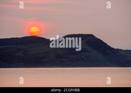 Lyme Regis, Dorset, Royaume-Uni. 11 septembre 2020. Météo Royaume-Uni. Vue de Lyme Regis dans Dorset au lever du soleil comme le soleil se lève à travers le nuage de noisettes mince de derrière le Cap d'or sur la côte jurassique. Crédit photo : Graham Hunt/Alamy Live News Banque D'Images