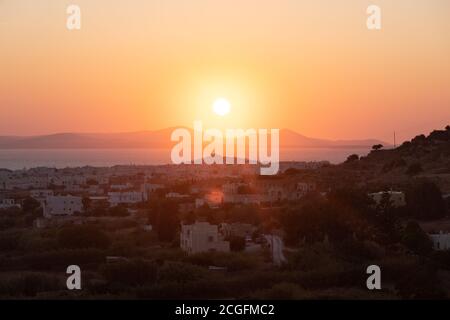 Un coucher de soleil orange sur la mer Égée à Mykonos, Grèce. Prise de la falaise surplombant la mer et les îles. Banque D'Images