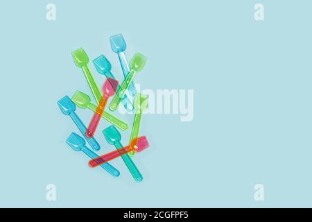 Cuillères à glace en plastique de couleur sur fond bleu clair Banque D'Images