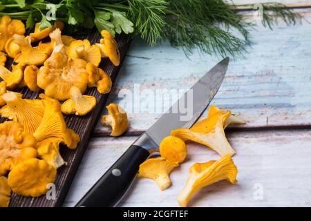 Les chanterelles se trouvent sur une planche en bois sombre, les petits pains d'aneth et le persil sur la table. L'automne est à venir Banque D'Images