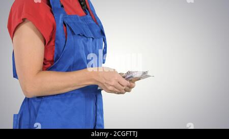 Une femme vêtue d'un travailleur compte de l'argent sur fond dégradé. Banque D'Images