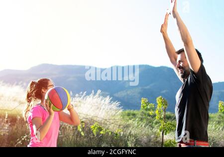 Père et fille jouent au basket-ball sourire heureux contre le coucher du soleil à Murcia, Espagne. Banque D'Images