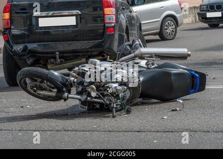 une moto cassée près de la voiture. un accident sur la route dans la ville par une journée ensoleillée impliquant une moto et une voiture. Banque D'Images