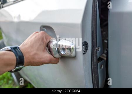 la main de l'homme ouvre la porte d'une voiture grise à proximité haut Banque D'Images