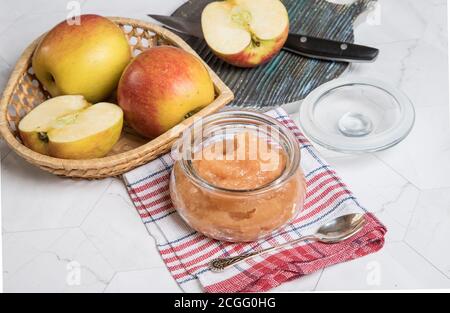 Purée de pommes dans un pot en verre et pommes fraîches sur fond clair. Gros plan. Orientation horizontale. Banque D'Images