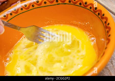 Battre les œufs dans un bol en argile avec une fourchette près haut Banque D'Images
