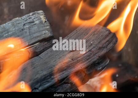 Charbon de bois chaud avec des flammes de feu de bois, brûlant gros plan. Foyer extérieur chaud en gros plan avec arrière-plan flou Banque D'Images