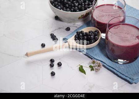 Sur un fond clair est une grande plaque avec des bleuets, deux verres avec un régime de bleuets smoothie stand sur un fond clair, une cuillère en bois avec be Banque D'Images