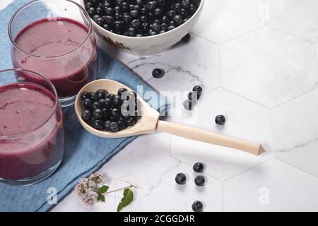 Sur un fond clair est une grande plaque avec des bleuets, deux verres avec un régime de bleuets smoothie stand sur un fond clair, une cuillère en bois avec be Banque D'Images