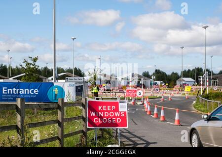Voiture entrant à l'entrée avec des panneaux pour Covid-19 conduire à travers le centre d'essai NHS coronavirus test et de l'installation de trace. York, North Yorkshire, Angleterre, Royaume-Uni Banque D'Images