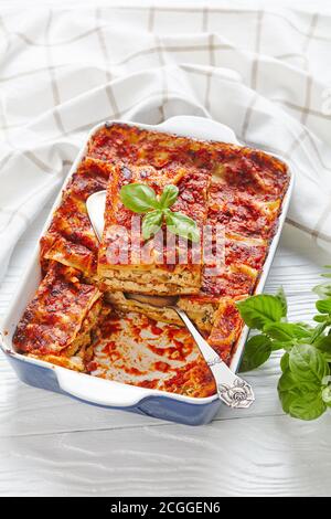 Lasagnes de tofu végétalien aux champignons champigny, sauce tomate, assaisonnement italien, cuit au four, servi sur un plat de cuisson aux herbes fraîches sur un blanc Banque D'Images