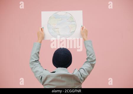 Écoactiviste femelle dans un chapeau tenant la bannière de terre de planète au-dessus de la tête, Banque D'Images