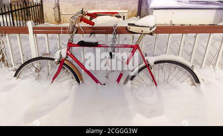 Un vélo rouge couvert de neige à moitié Banque D'Images