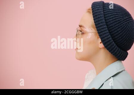 Portrait latéral de la jeune femme en casquette, verres ronds avec un visage sérieux. Banque D'Images