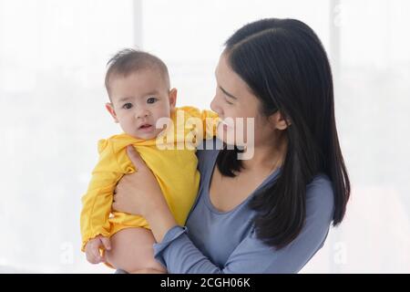 Une mère asiatique porte son bébé avec amour et soin. Banque D'Images