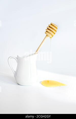 Le miel coule du bâton de miel en dinde. Les miels font sur fond blanc. Carafe à crème pour le petit déjeuner Banque D'Images