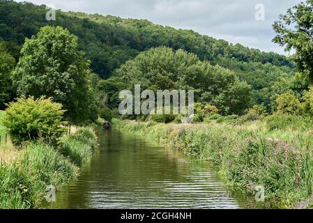 Une vue sur le canal rural de Kennet et Avon à bord d'un bateau à narrowboat, avec un autre au loin, entouré d'arbres verts et de collines Banque D'Images